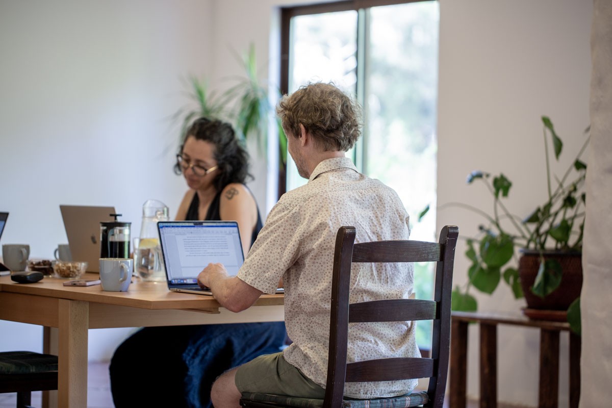 Two remote workers on their laptops at a shared table at Satvana in Portugal
